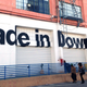Two people walk past the American apparel factory building and outlet store in Los Angeles, California July 7, 2014. Ousted American Apparel Inc head Dov Charney supported workers in the clothing industry with his stance in favor of immigration rights and determination to keep jobs in the United States, but some employees are not returning the favor. Last month American Apparel's board dismissed Charney. It accused the chairman, president and chief executive of misusing corporate funds and failing to prevent the dissemination of nude photos of a female ex-employee who sued him. Picture taken July 7, 2014.